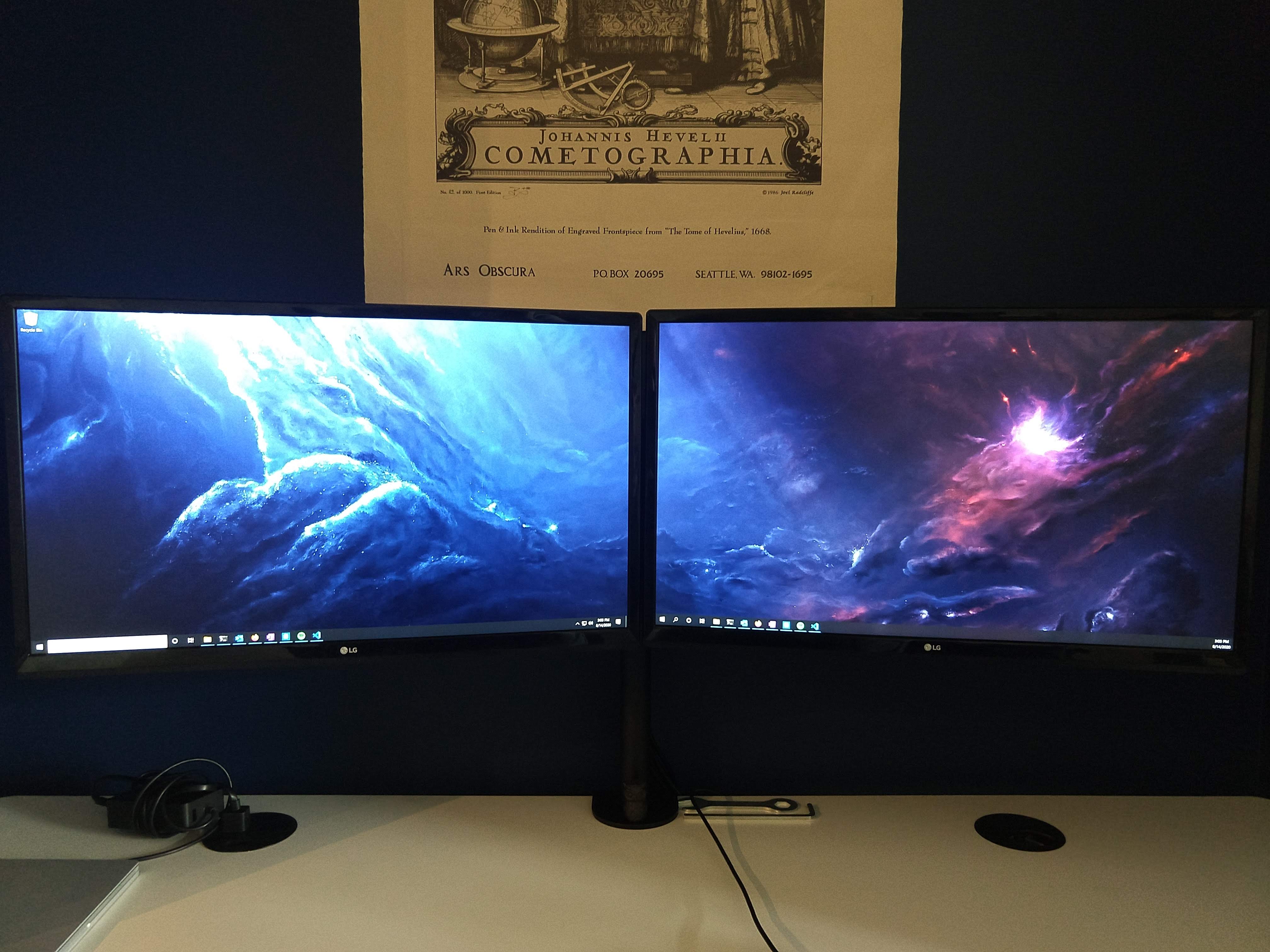 Photo of two monitors set up symmetrically in landscape mode. A photo of a nebula fills the screens.